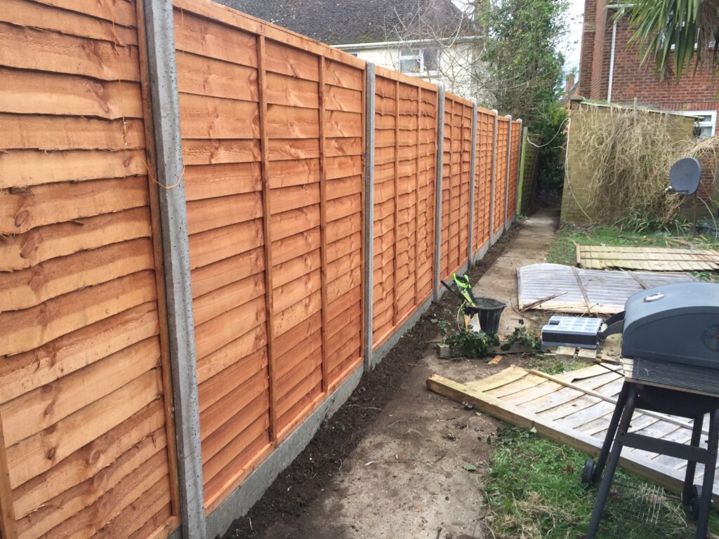 Waney lap fence panels with concrete posts and gravel boards