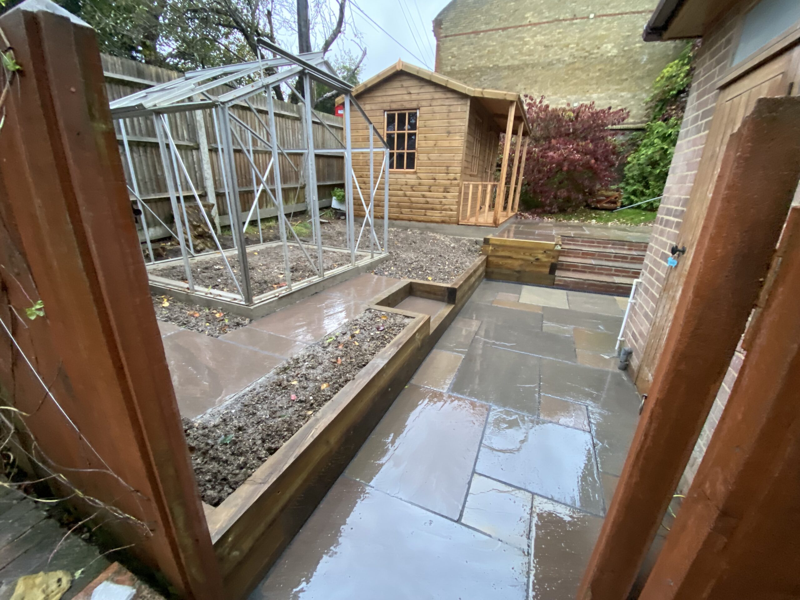 Indian sandstone patio with garden steps and sleeper edging