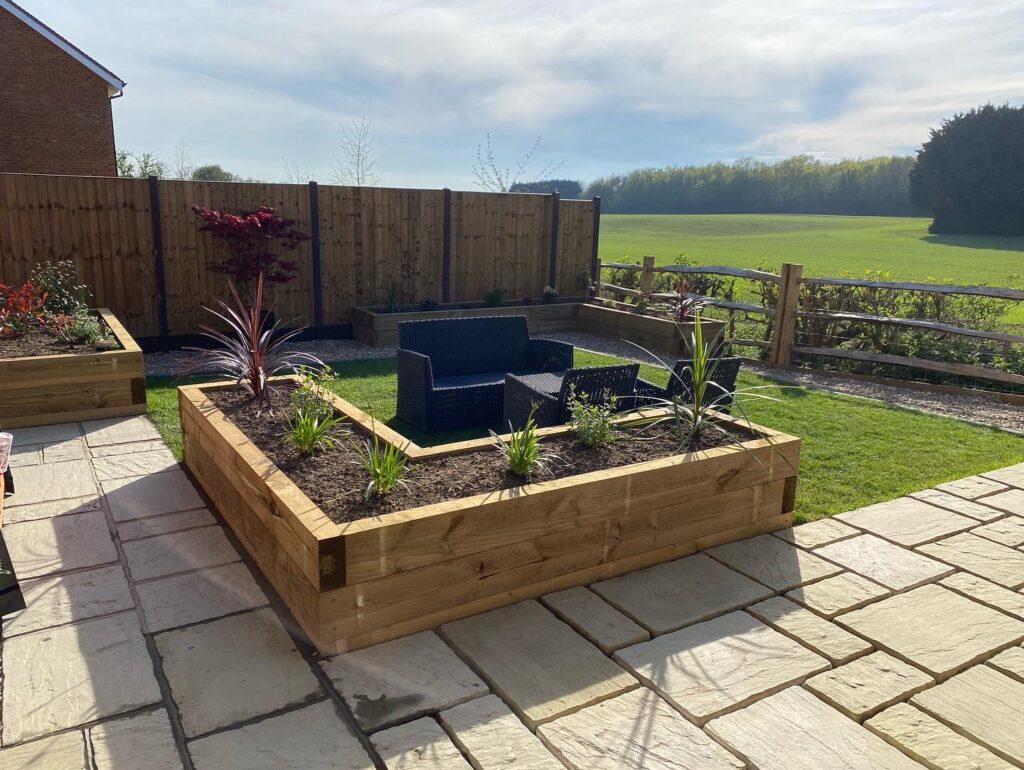 Raised sleeper planter with planting beside a paved patio in Maidstone