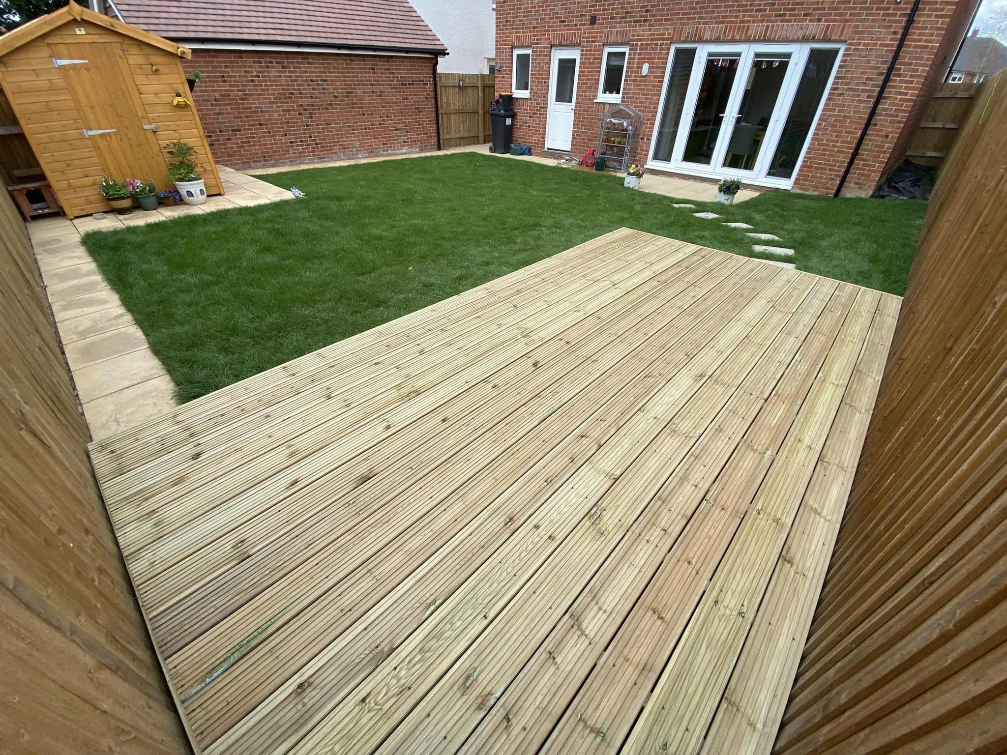 Timber garden decking installed beside a lawn in Maidstone