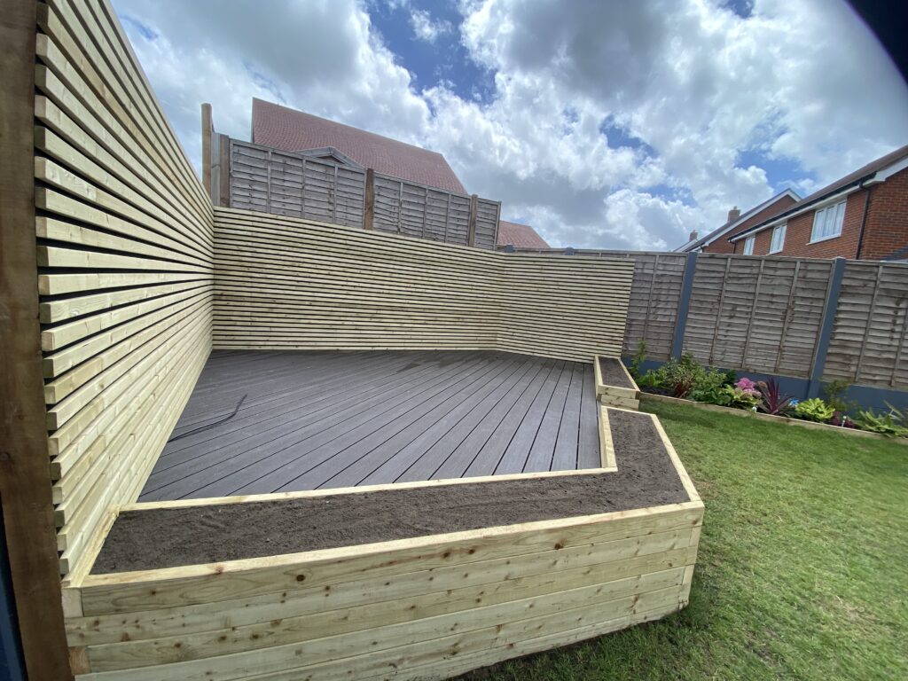 Composite decking with timber sleeper planter and slatted privacy screening