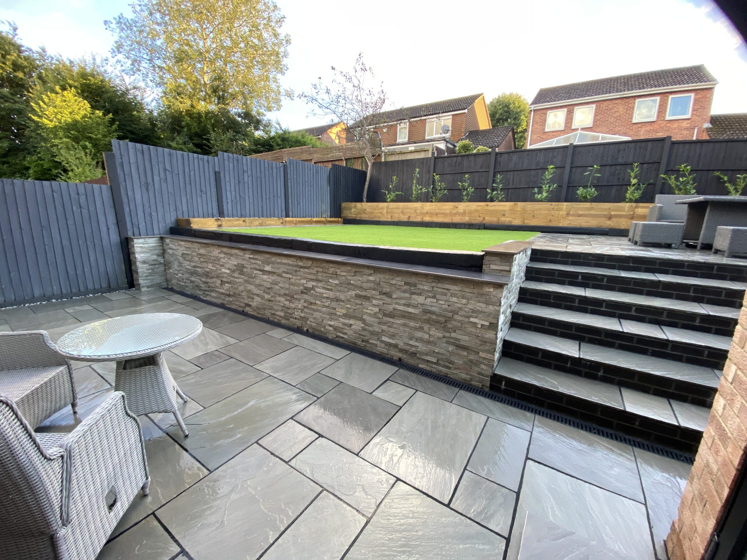 Landscaped garden with sandstone paving and raised sleeper planters