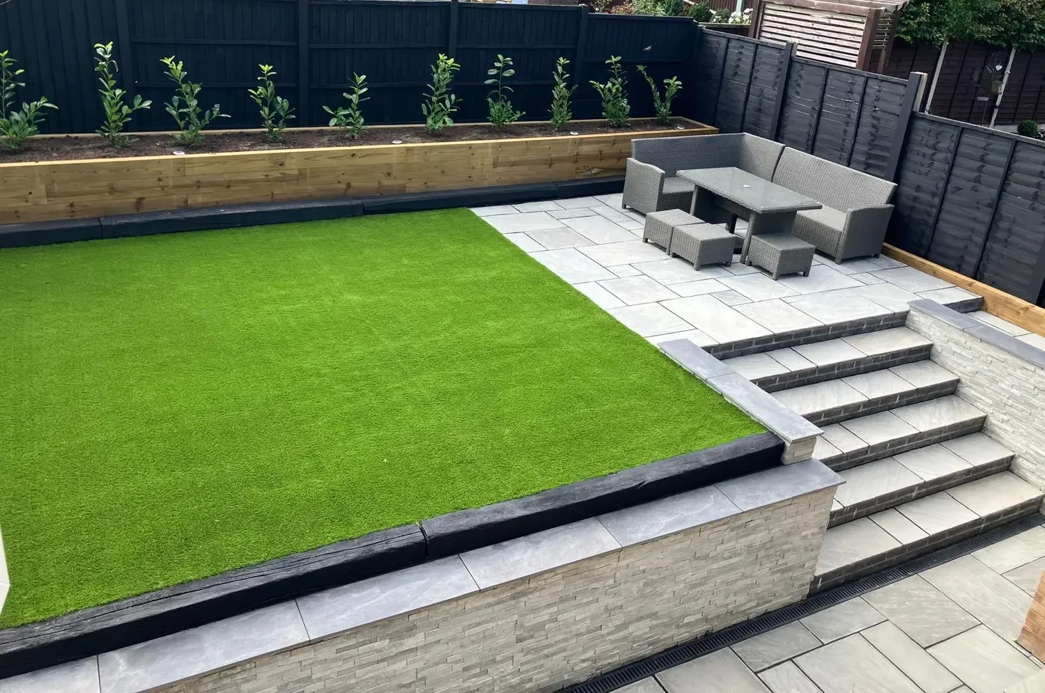 Raised garden with porcelain paving and sleeper planters