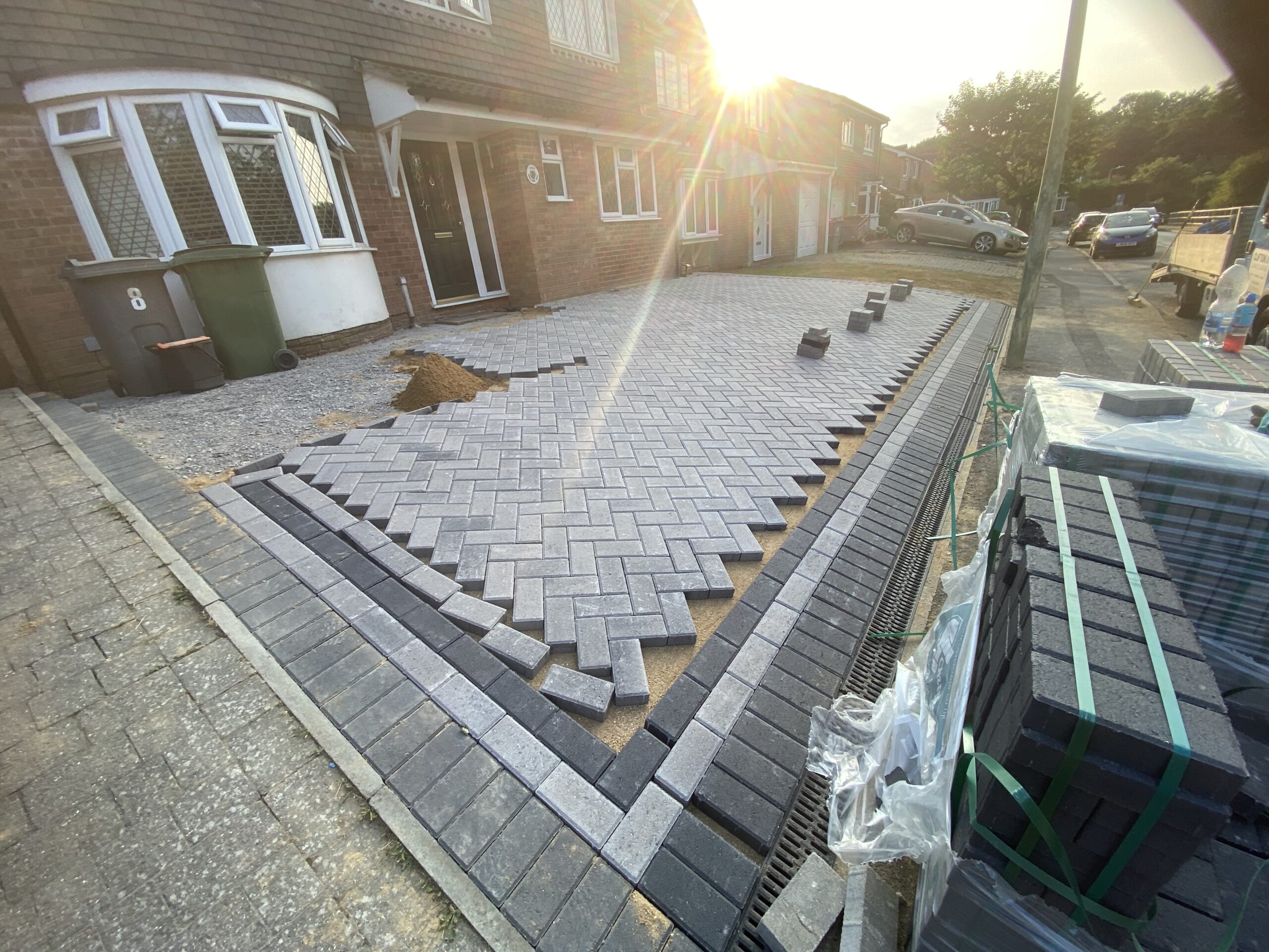 Block paving being laid in herringbone pattern with dark border edging