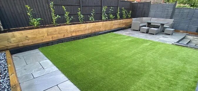 Artificial grass with raised sleeper planter and porcelain patio in Maidstone