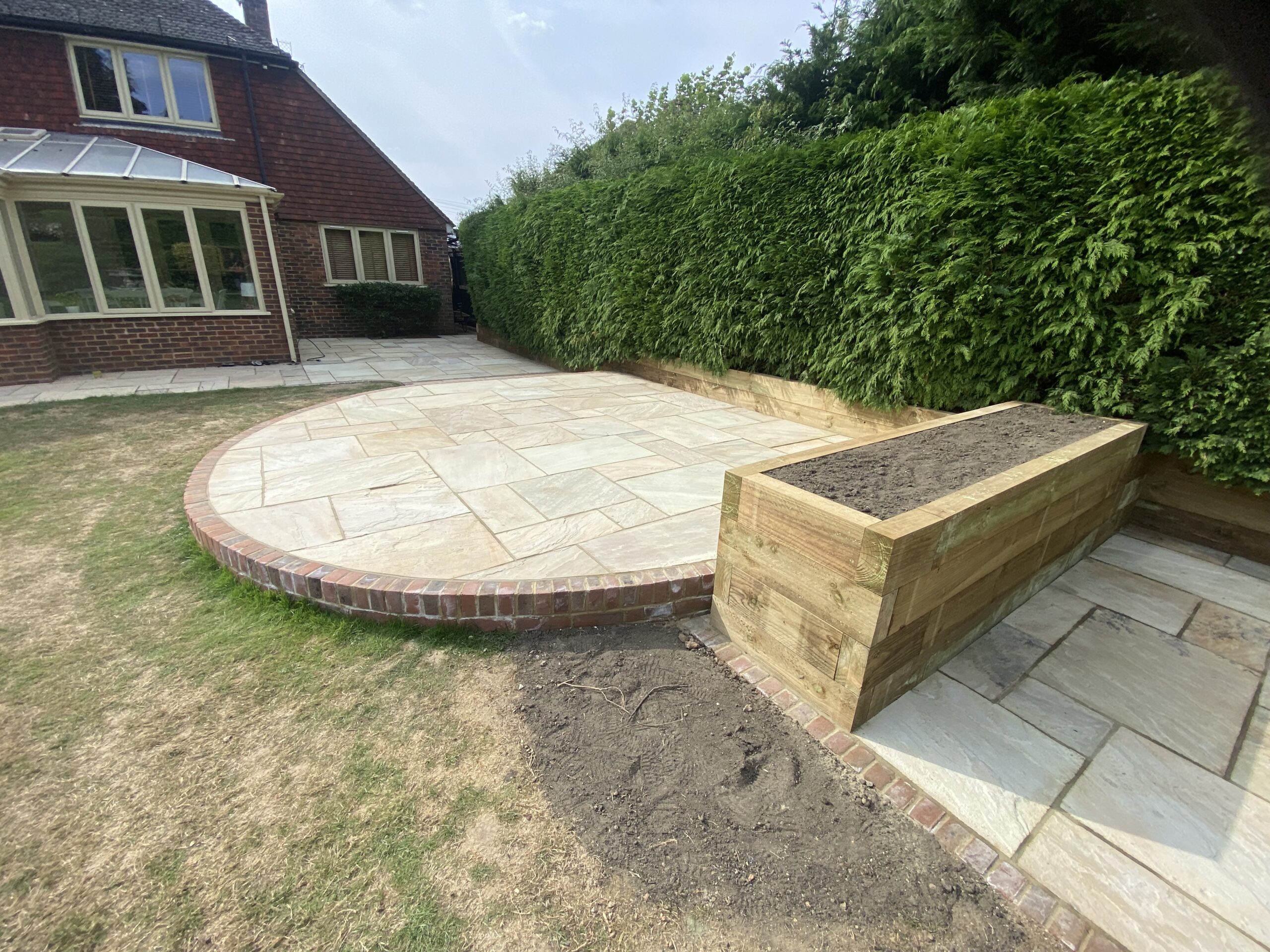 Modern garden transformation with porcelain patio, artificial grass and raised sleeper planters
