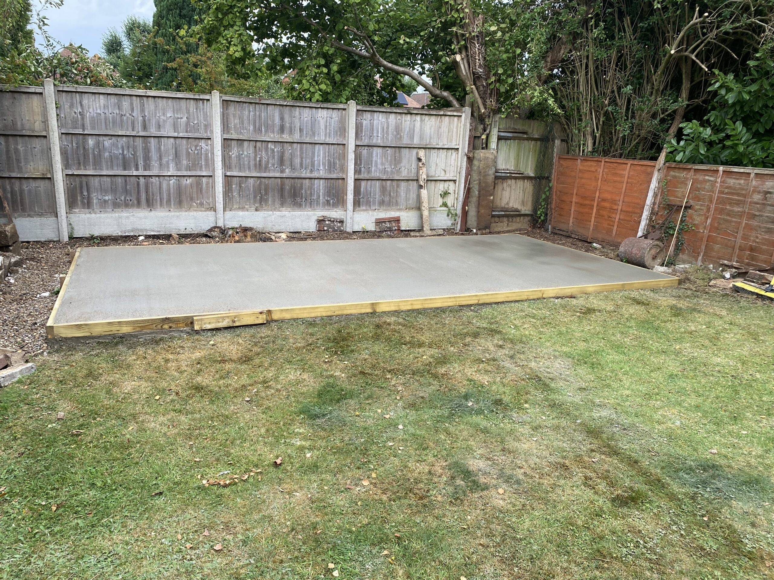 Finished concrete shed base with timber shuttering in a garden