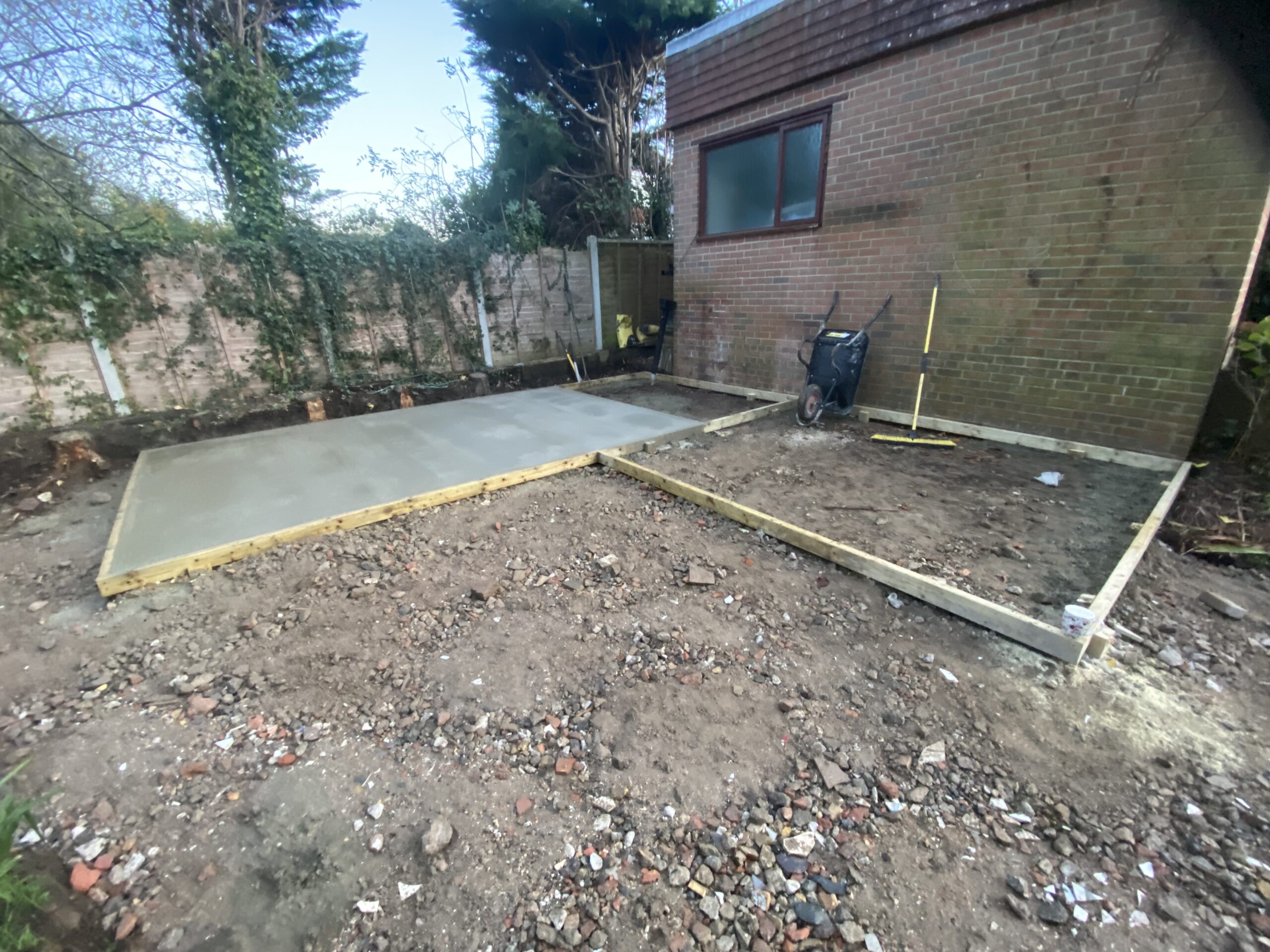 Finished concrete shed base beside a brick building