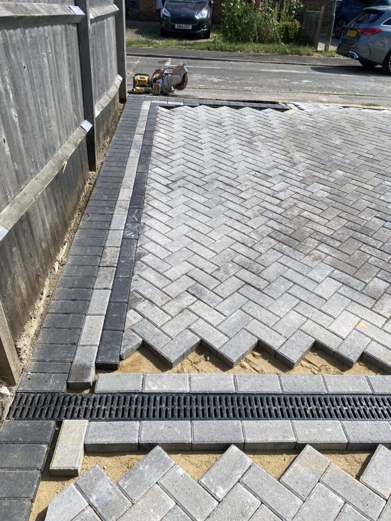 Grey block paving being installed with contrasting dark border