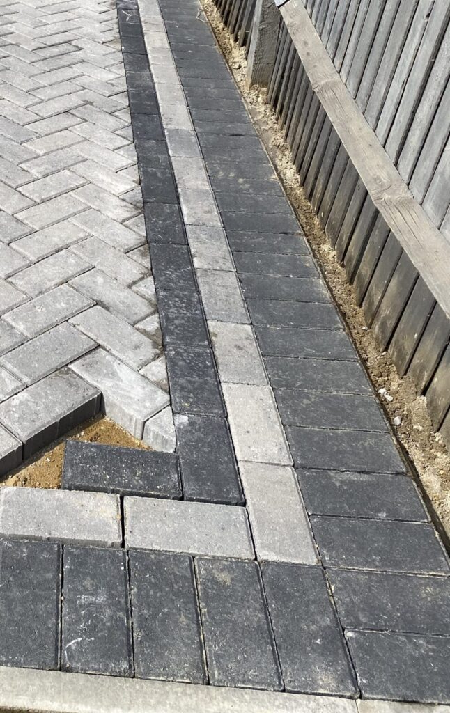 Block paving border being cut and fitted around driveway edging